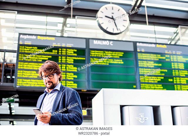 Low angle view of businessman using smart phone at railroad station