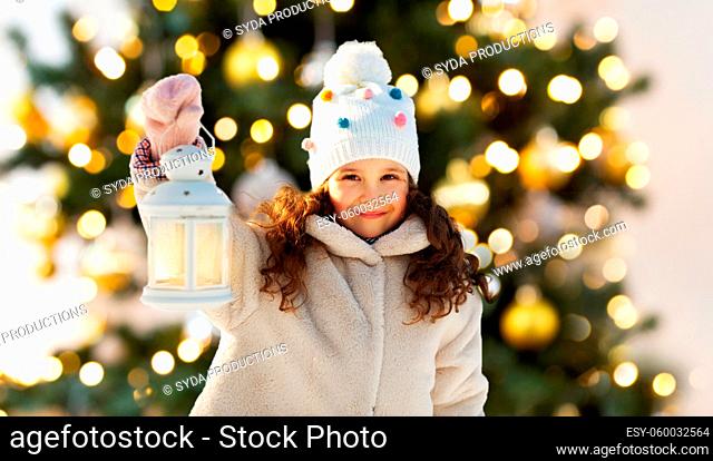 happy little girl with lantern over christmas tree