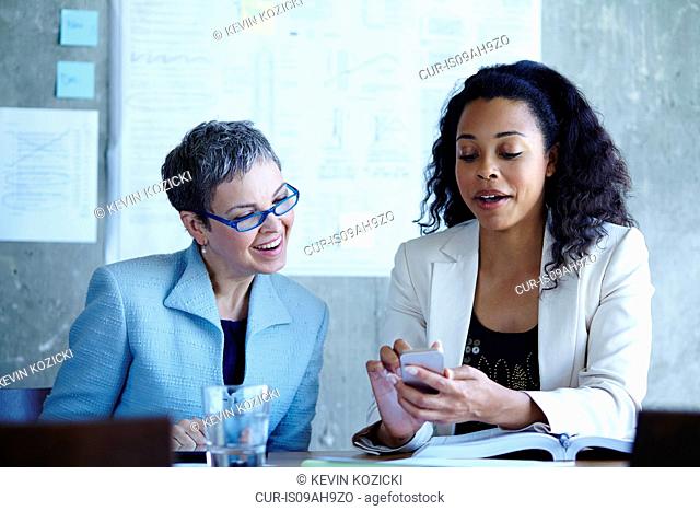 Two businesswomen distracted by smartphone