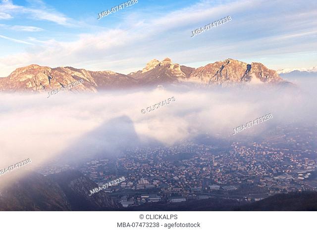 Monte Barro casts its shadow on the fog illuminates by sun, with Corni di Canzo group in the background, Monte Barro Regional Park, Brianza, Lombardy, Italy