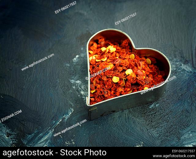 Hot organic chili flakes in a heart shaped cookie cutter, spicy ingredients, healthy food