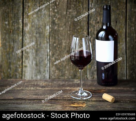 Wine bottle with glass of red wine over wooden background