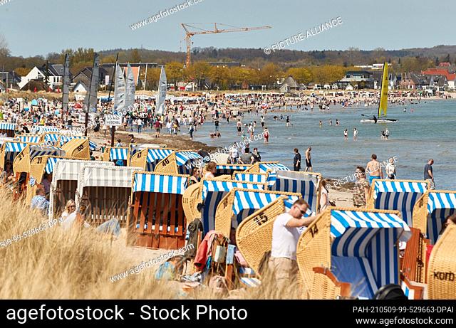 09 May 2021, Schleswig-Holstein, Scharbeutz: Thousands of people enjoy the sunny and warm weather on Sunday afternoon next to beach chairs on a beach in the Bay...