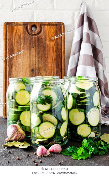 Canned zucchini and fresh vegetables for the winter. Sliced zucchini with parsley and garlic, homemade vegetables preserves in glass jar