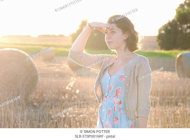 Girl shielding her eyes in hay field