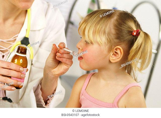 CHILD AT HOSPITAL CONSULTATION Models. Studio shot. The doctor is giving a spoon of syrup to a child syrup against loose cough
