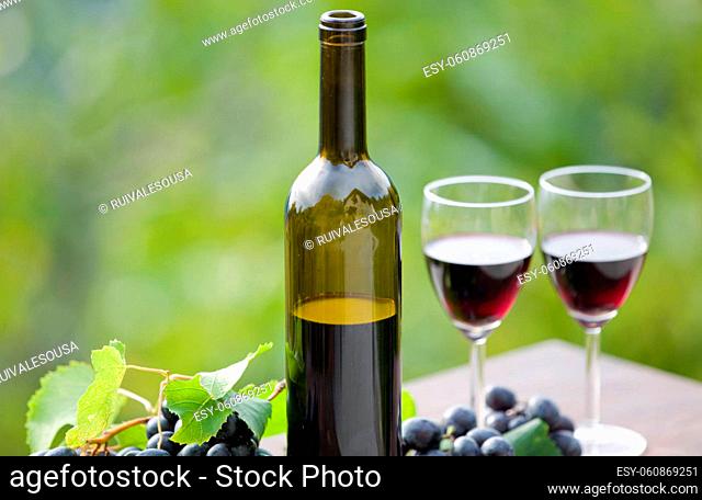 wine bottle and grapes on wooden table outdoor