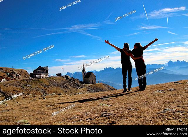 two hikers, female hikers, joyful, Latzfons, Sarntal Alps, Bolzano Province, South Tyrol, Italy, Europe. The refuge and the pilgrimage church Latzfonser Kreuz...
