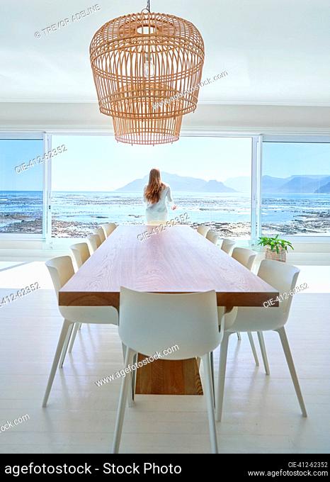 Woman standing at open dining room patio door with ocean view