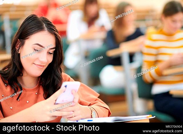 female female students use a smartphone during classroom instruction