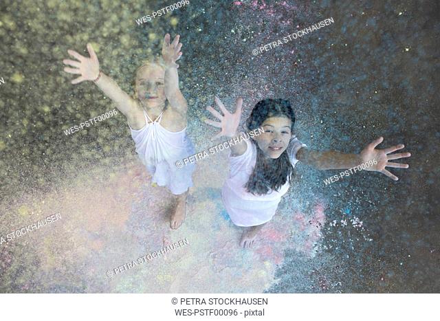 Portrait of two friends throwing colour powder in the air