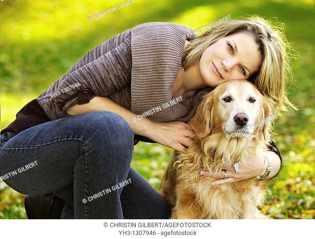 Beautiful young woman posing in front of the camera with her Golden Retriever dog