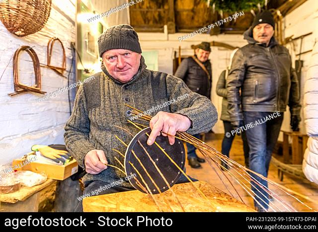 02 December 2023, Brandenburg, Lehde: In a house in the Lehde Open-Air Museum, a craftsman makes a bird feeder from willow rods