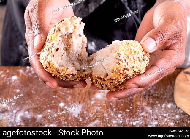 Close-up of african american male baker breaking bread on table