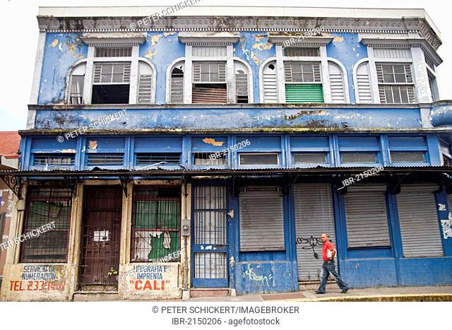 Lone passerby walking in front of a dilapidated building in the town centre of San Jose, Costa Rica, Central America