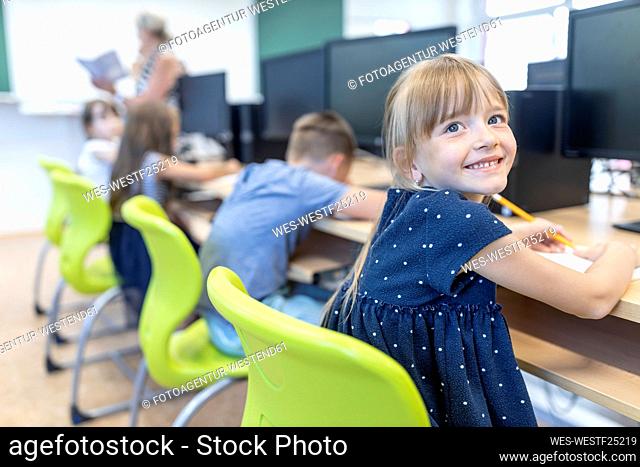 Smiling girl contemplating sitting at desk in classroom