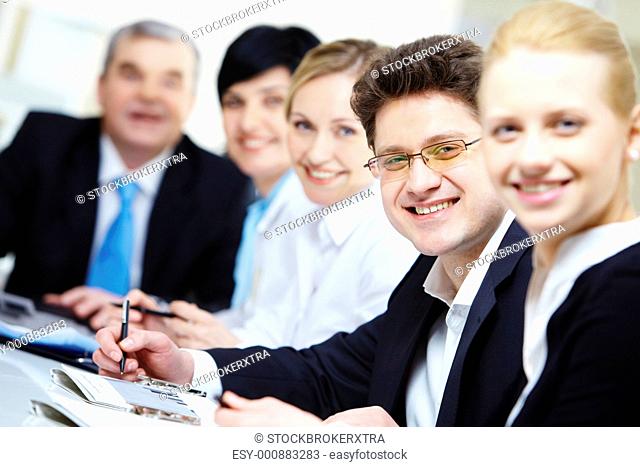 Confident businessman looking at camera among colleagues