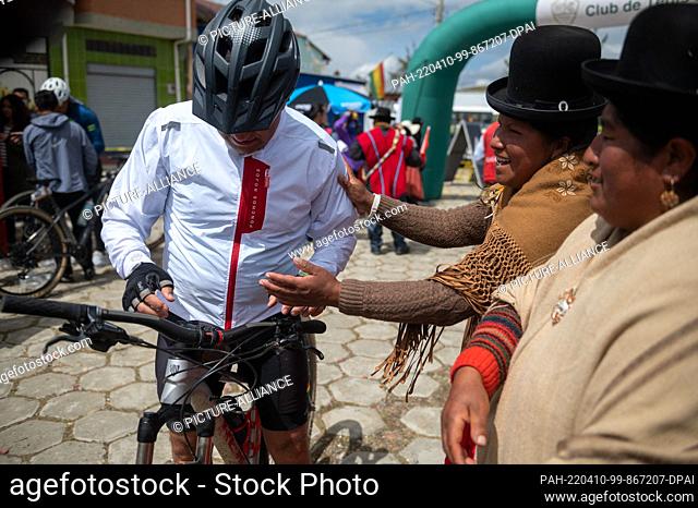 09 April 2022, Bolivia, Jankho Amaya: Local women congratulate a cyclist after he finishes the bike race. The ""Poncho rojo"" (red poncho) race