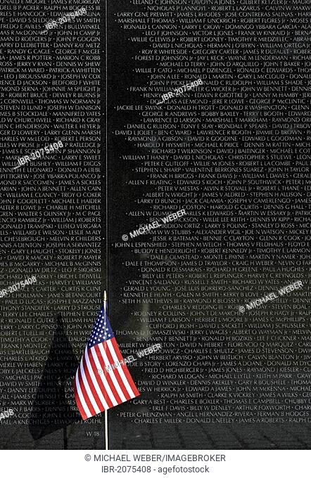 US flag in front of the Vietnam Veterans Memorial Wall, national memorial with the names of fallen US soldiers during the Vietnam War, Washington DC