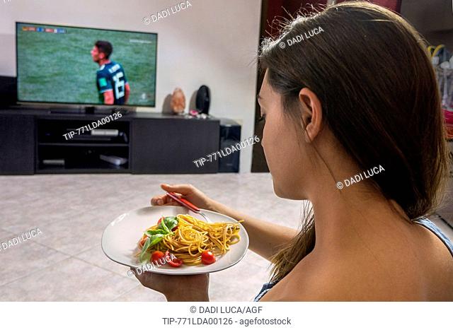 young woman eating wholemeal spaghetti with tomatoes and basil