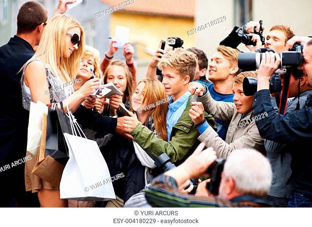 Young celebrity signing autographs for a crowd of young fans