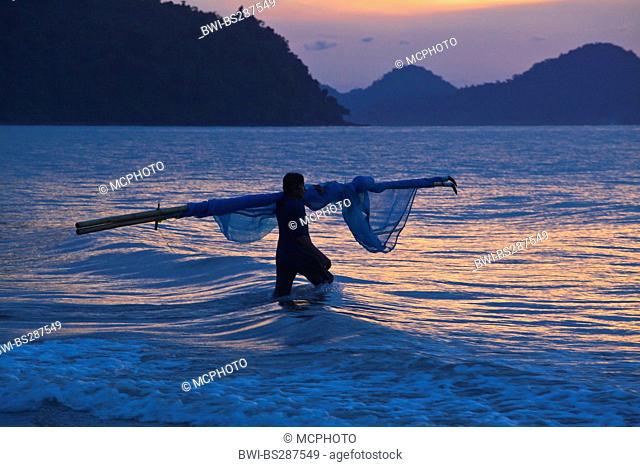 a fisherman wading into the sea to set his fishing nets, Thailand