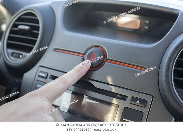 Woman pressing hazard lights button. Inside car view