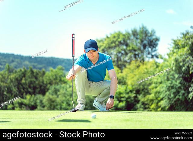 Golf player carefully taking measure to hole in on the green
