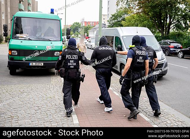 15 July 2020, Berlin: A man (3rd from right) is accompanied by two police officers to a police vehicle during a police operation in Berlin-Gesundbrunnen as part...