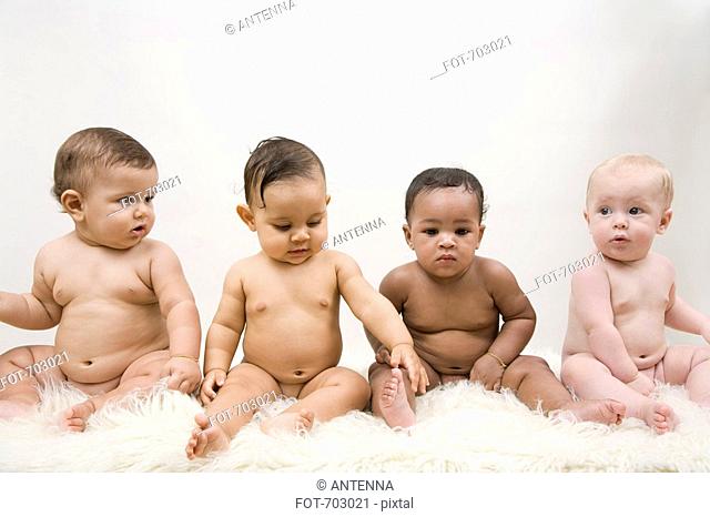Four babies sitting in a row