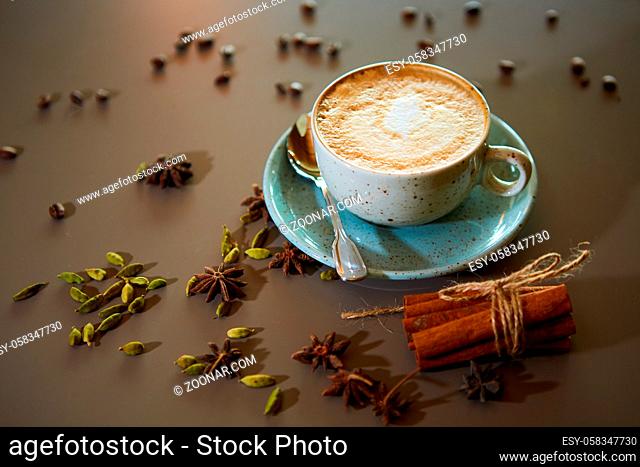 Cup of hot latte coffee on table with spices