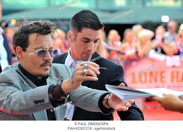 FILE - A file picture dated 19 July 2013 shows US actor Johnny Depp signing autographs during the premiere of his film Lone Ranger, in Berlin, Germany