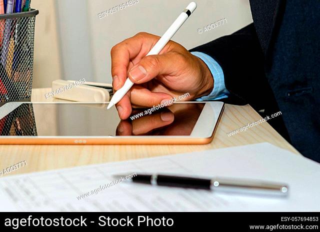 Business men are using a tablet with business documents and pens at desk. Work from home