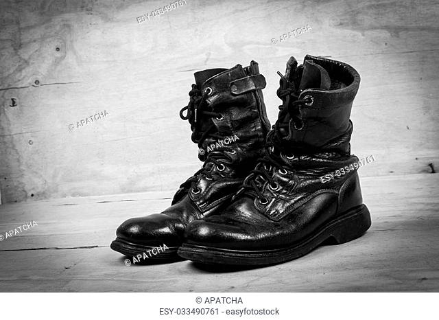 old black combat boots on wooden background, black and white tone