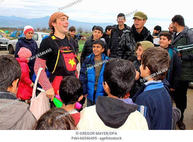 A member of the group 'Rebel Clowns' speaking with children in the refugee camp at the Greek-Macedonian border in Idomeni, Greece, 9 March 2016