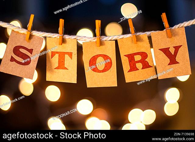 The word STORY printed on clothespin clipped cards in front of defocused glowing lights