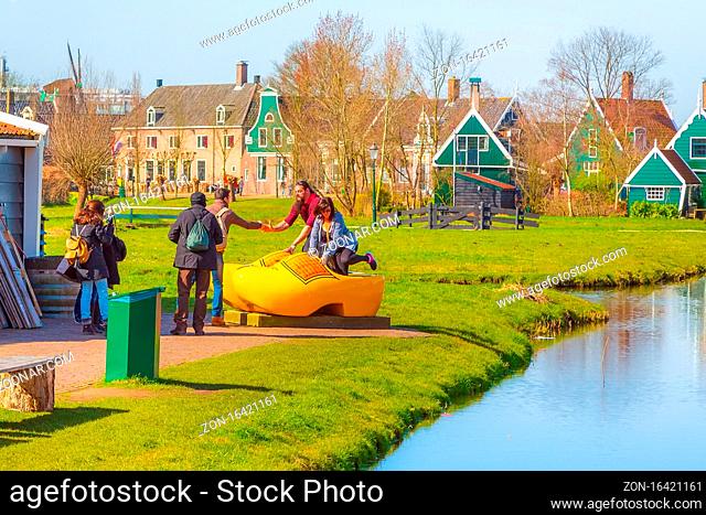 Zaanse schans, Netherlands - April 1, 2016: Large yellow wooden shoes, clogs or klompens for taking photo in Holland, people