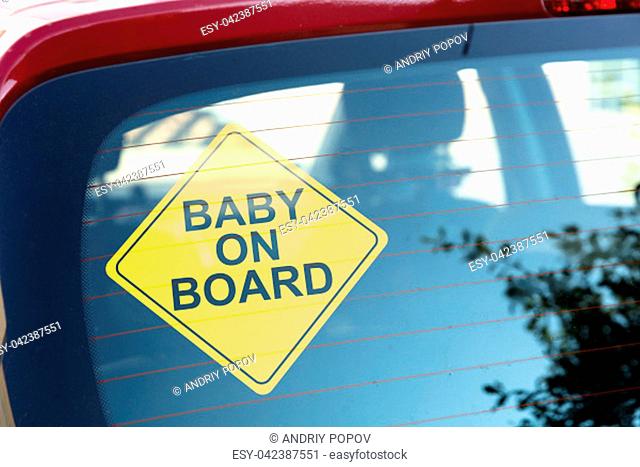 Close-up Of Yellow Baby On Board Sticker On Car Back Window