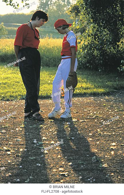Mother talking to daughter in baseball uniform