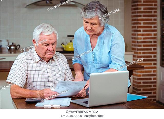 Retired couple calculating bills with laptop