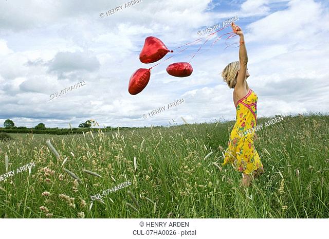 Woman walking with balloons in field