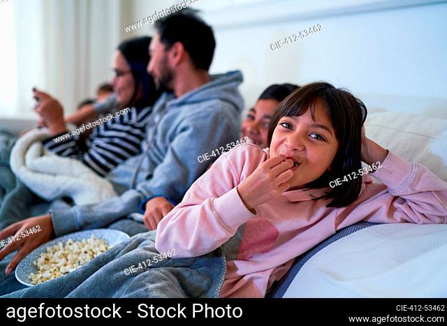 Portrait happy girl eating popcorn on sofa