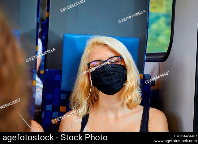 Young woman travelling on a train wearing facemask