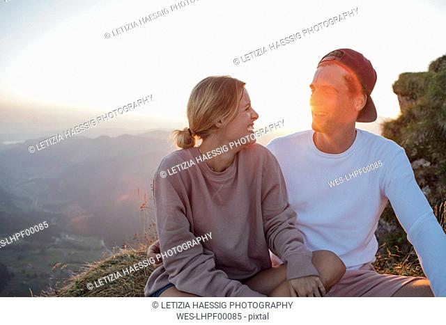 Switzerland, Grosser Mythen, happy young couple on a hiking trip having a break at sunrise
