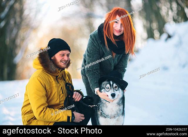 couple playing with the dog in the park in winter