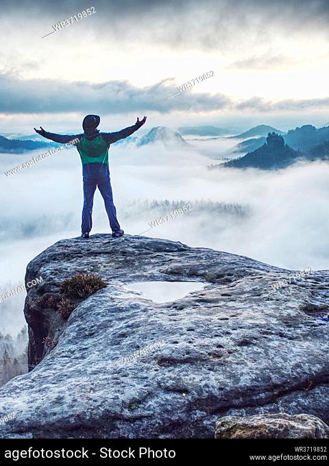 Man on successful hiking trip, silhouette in low mountains of Saxony Switzerland. Hiker on top of mountain looking at beautiful misty landscape