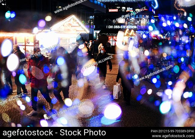 dpatop - 15 December 2020, Berlin: Passers-by walk through Castle Street with shopping bags past stalls as they go Christmas shopping. From 16.12