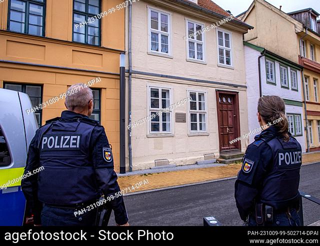 09 October 2023, Mecklenburg-Western Pomerania, Schwerin: Police officers stand with their patrol car in front of a building behind which the synagogue and the...