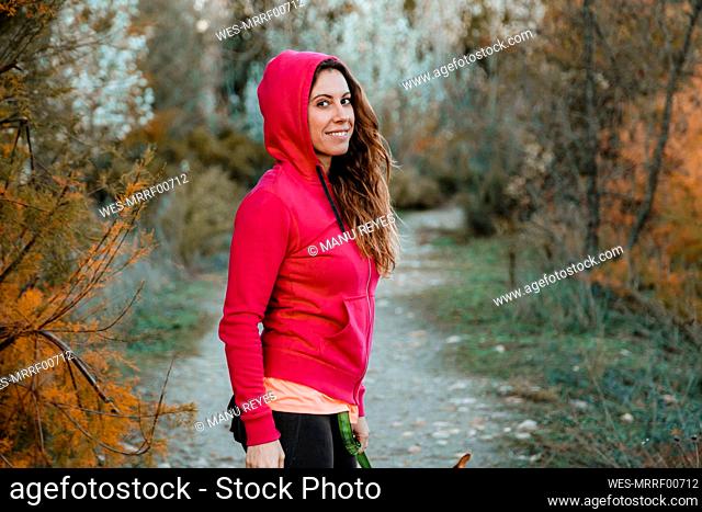 Smiling woman in red hooded shirt at countryside