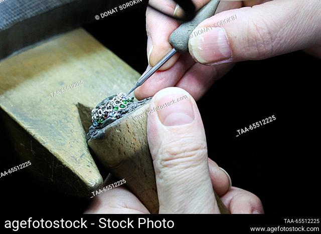 RUSSIA, YEKATERINBURG - DECEMBER 6, 2023: A worker employs the Russkaya Zakrepka stone setting technique to inlay an item with tsavorite at the Moiseikin...